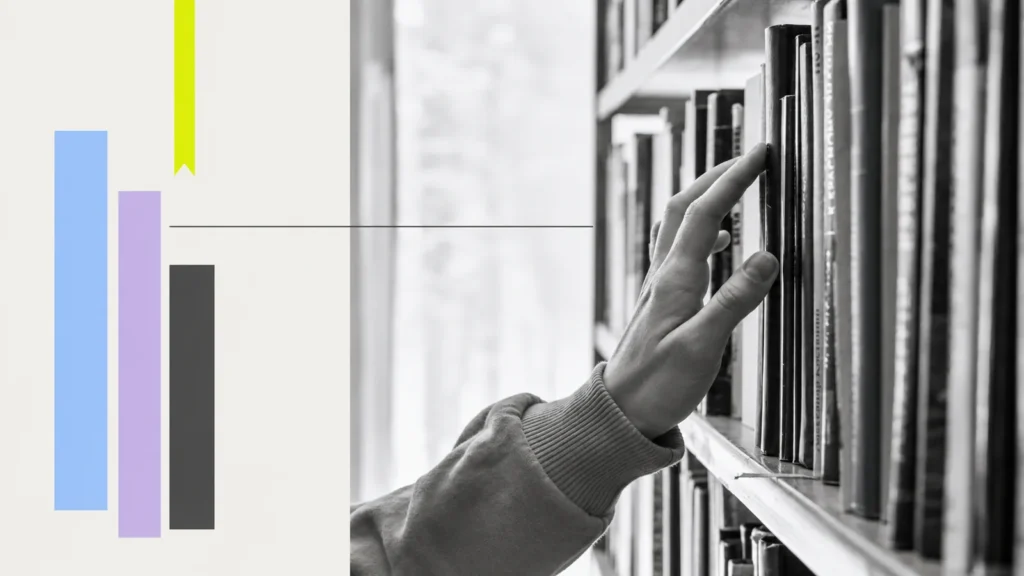 A hand selecting a book from a shelf.