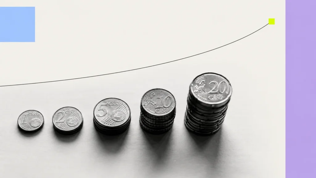 Stacks of euro coins increasing in height beneath a rising curved line, with coloured geometric accents.